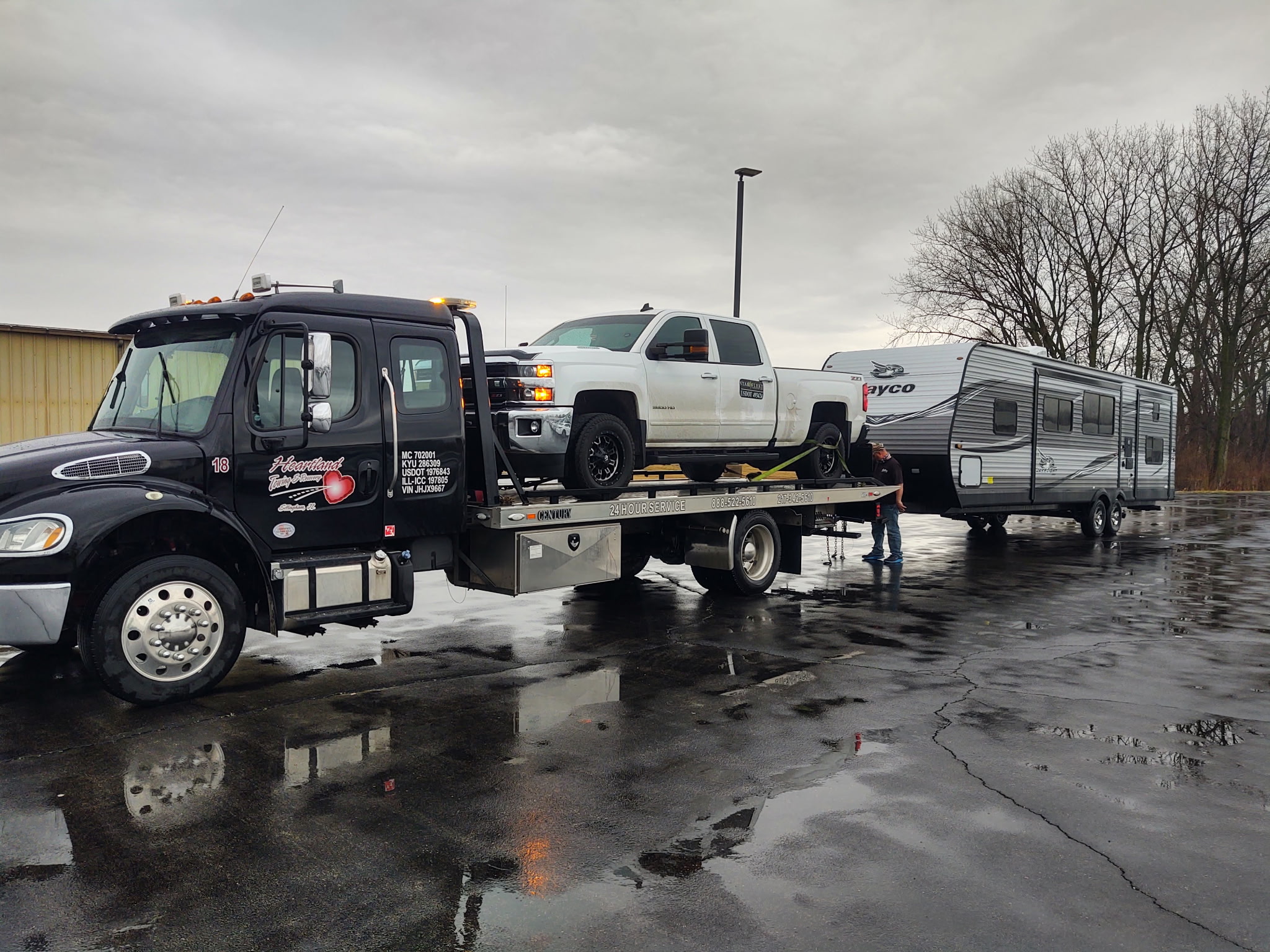 Heartland black rollback with a pickup and camper